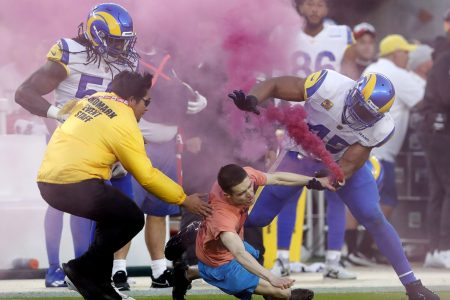 A protester with a pink smoke bomb is tackled by Bobby Wagner of the Los Angeles Rams at Levi's Stadium in Santa Clara, California