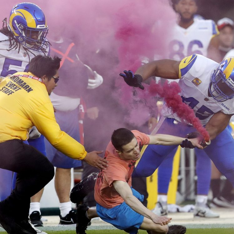 A protester with a pink smoke bomb is tackled by Bobby Wagner of the Los Angeles Rams at Levi's Stadium in Santa Clara, California