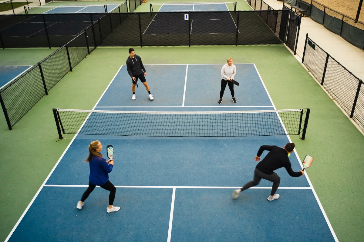 A group of young adults playing Pickleball on an outdoor court