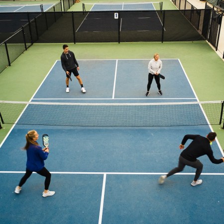 A group of young adults playing Pickleball on an outdoor court