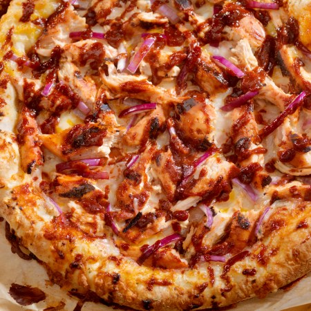 bbq chicken pizza with red onions on parchment paper