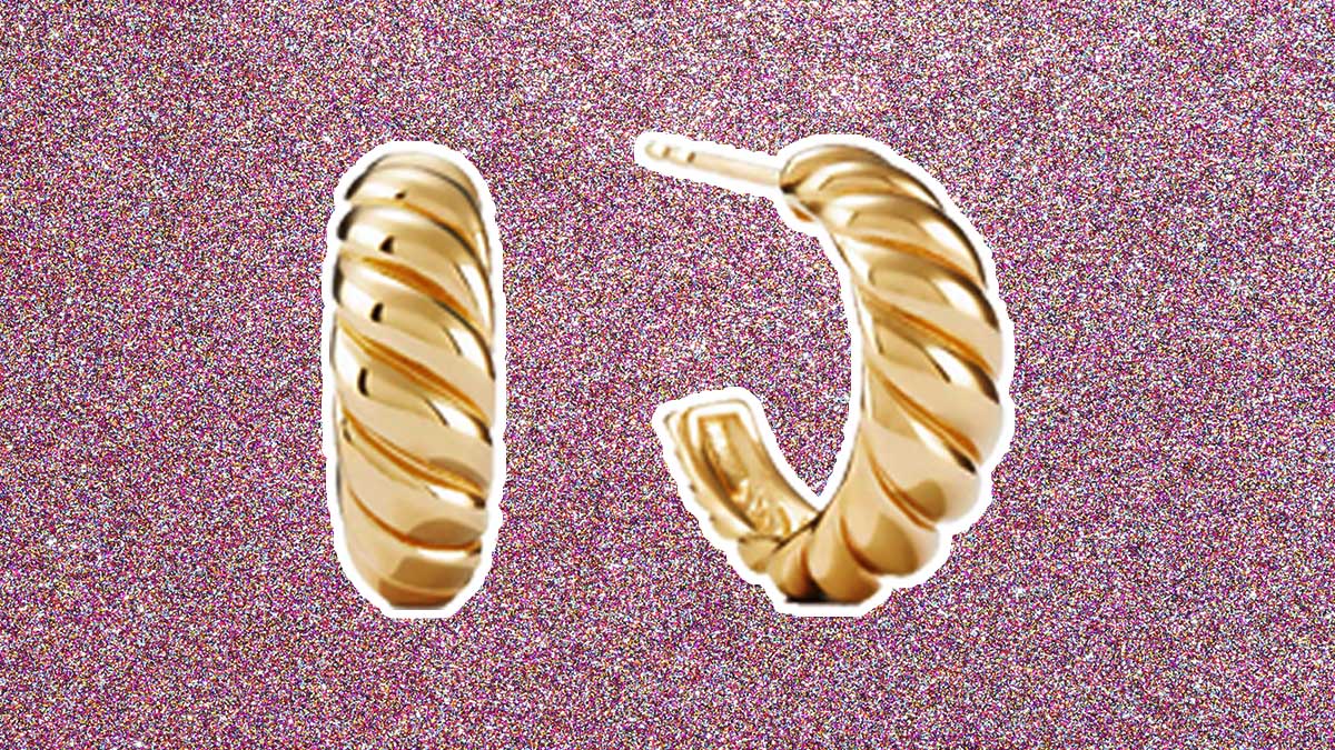 The Mejuri Croissant Dôme Hoops, on a pink glittery background