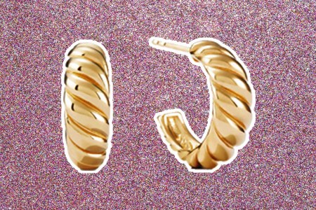 The Mejuri Croissant Dôme Hoops, on a pink glittery background