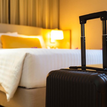 A black suitcase sitting in front of a bed in a hotel room. A new survey looks at the number of mattresses stolen from hotels.