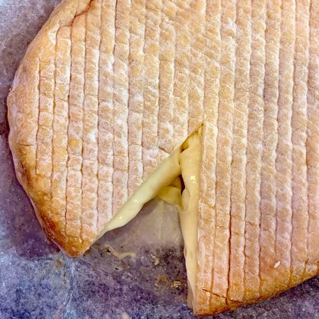 soft washed rind cheese wheel with one piece cut out