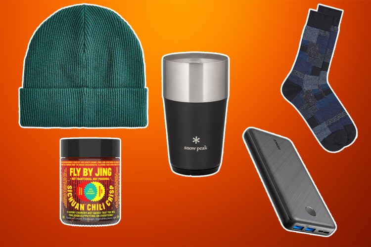 Stocking stuffer items like a snowpeak tumbler, J.Crew Beanie and Anker charger on a orange and rust colored background