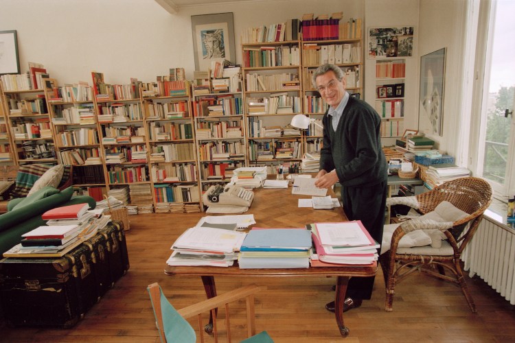 An Italian writer standing in a home library.