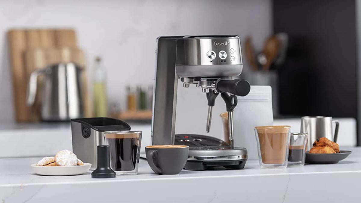 A Breville Express espresso machine on a counter with a few cups of coffee. Amazon is hosting a sale on these machines.