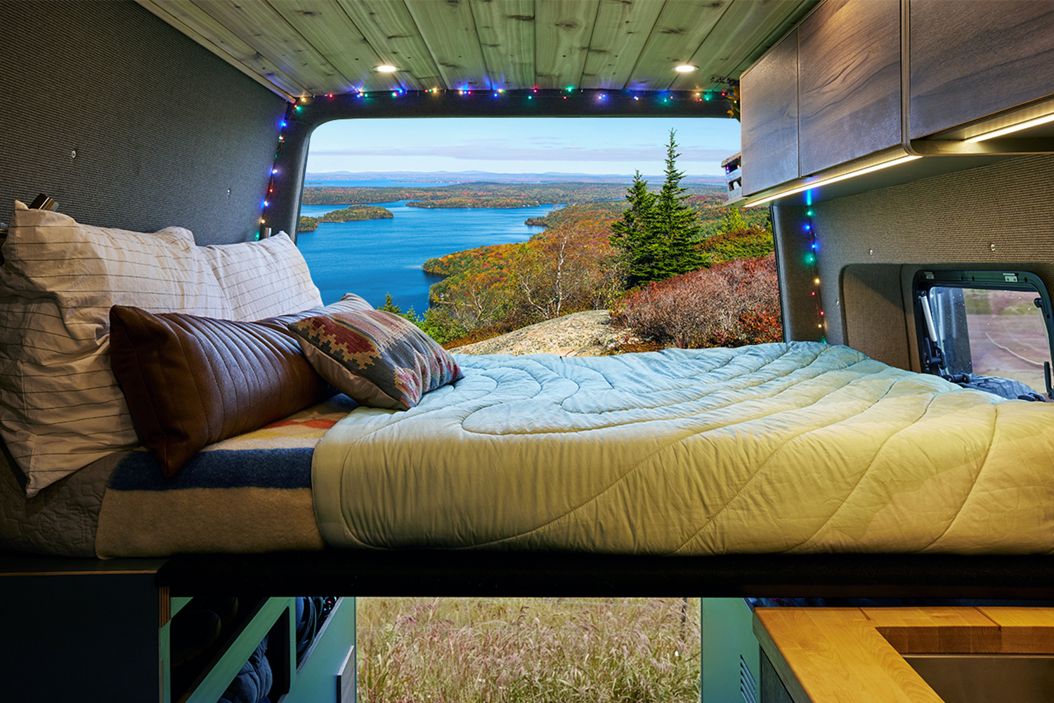 A view out onto a lake and forest from the back of a Mercedes-Benz Vansmith Sprinter Van being given away by Omaze