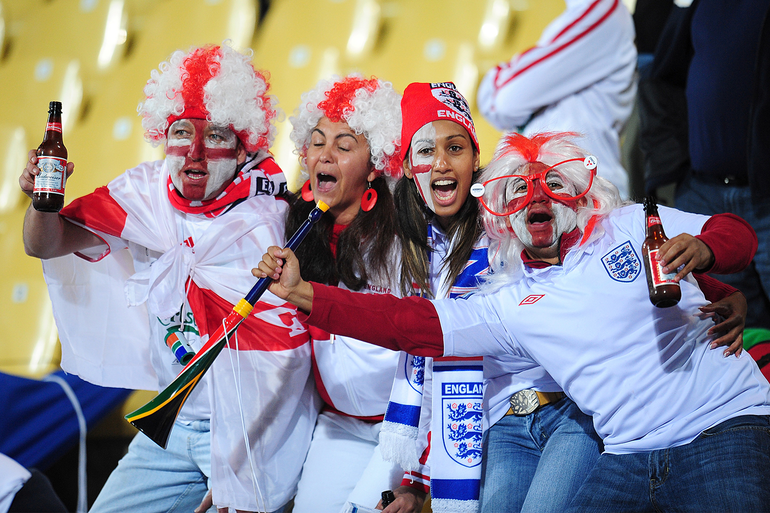 Four England fans holding beer and wearing face paint at the 2010 World Cup in South Africa. The 2022 edition in Qatar will look much different.