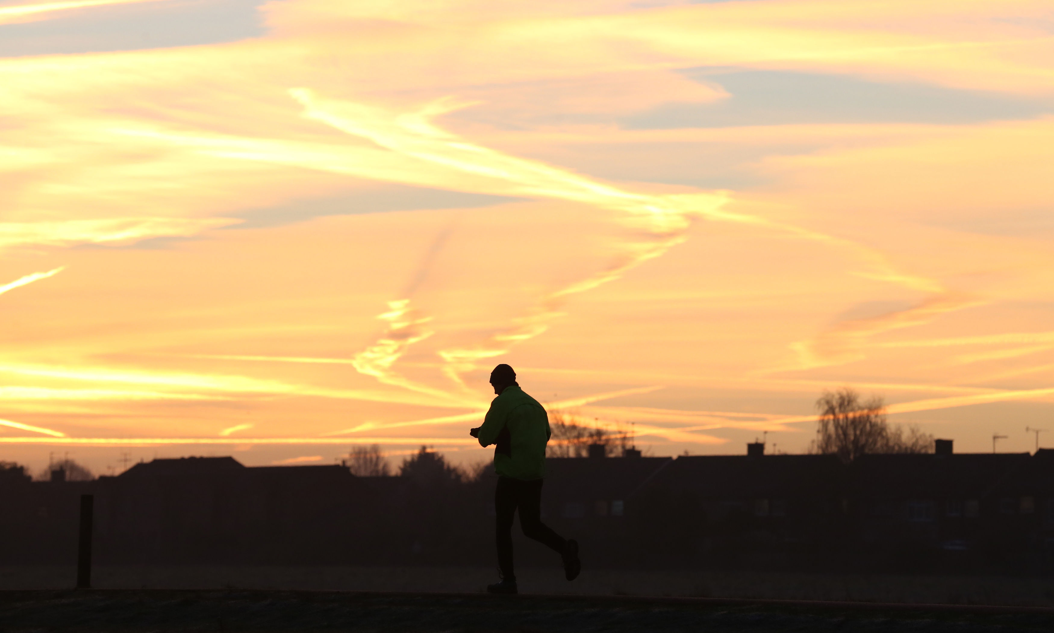 A man gets ready to jog in the countryside at sunrise.