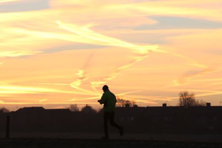 A man gets ready to jog in the countryside at sunrise.