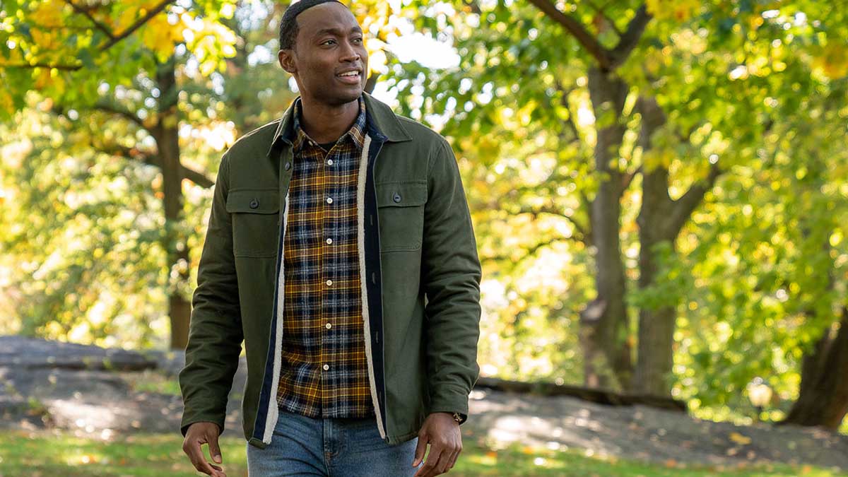 A man wearing various Jachs NY clothing (jacket, shirt, jeans) standing outside in a brightly-lit forest. JACHS NY is currently throwing a Black Friday sale.
