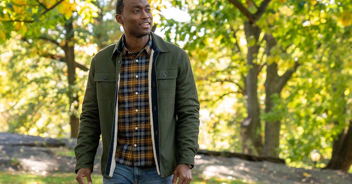 A man wearing various Jachs NY clothing (jacket, shirt, jeans) standing outside in a brightly-lit forest. JACHS NY is currently throwing a Black Friday sale.