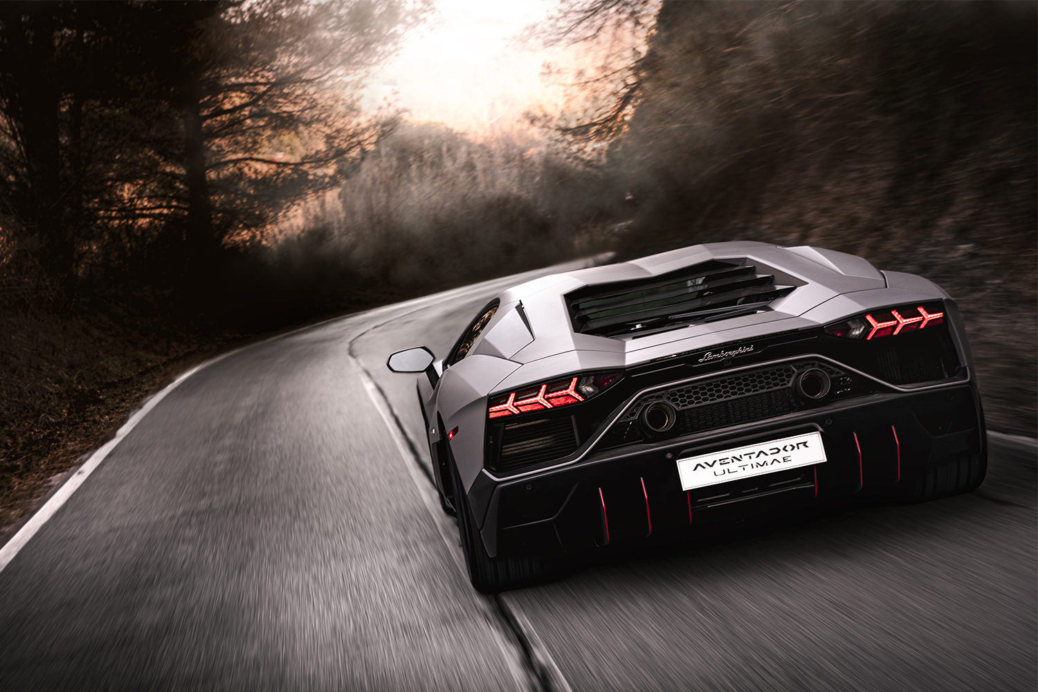 A Lamborghini Aventador Ultimae shown from the rear driving down a road at dusk