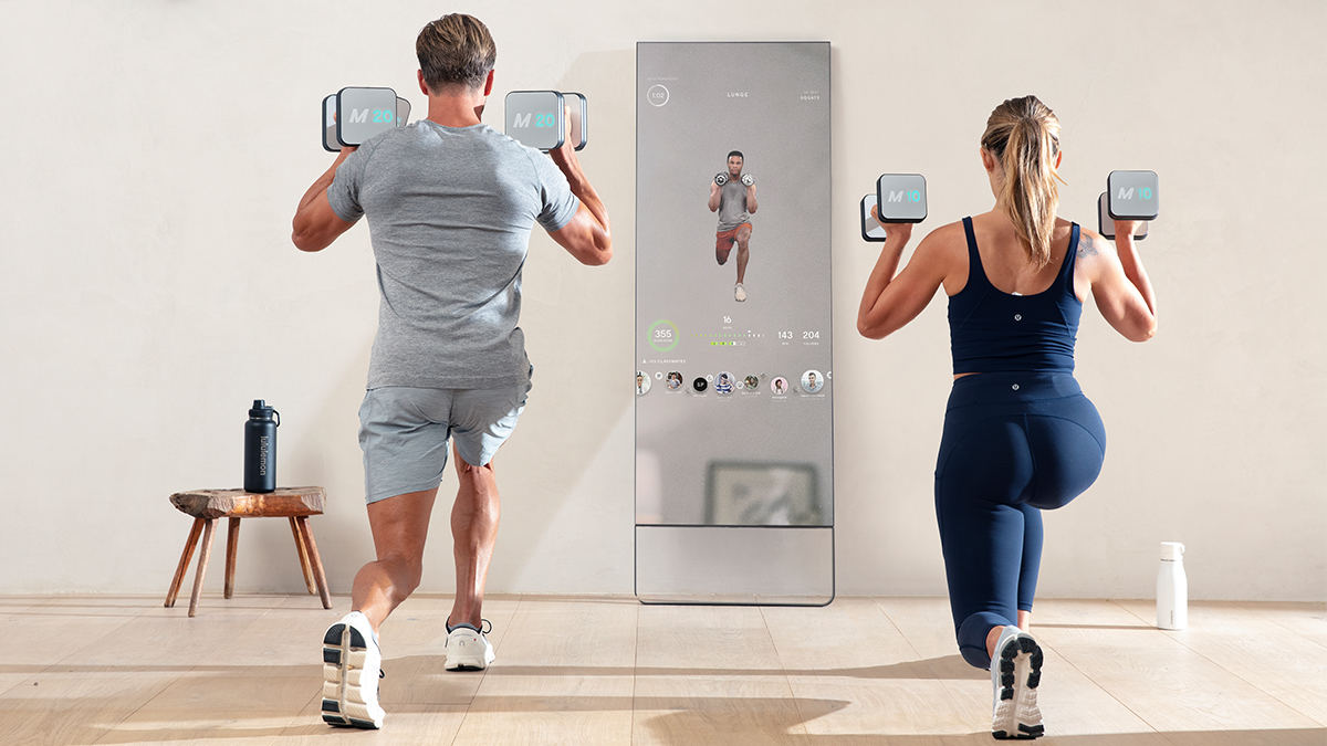 A man and woman working out with the Lululemon Studio Mirror, which is currently 50% off