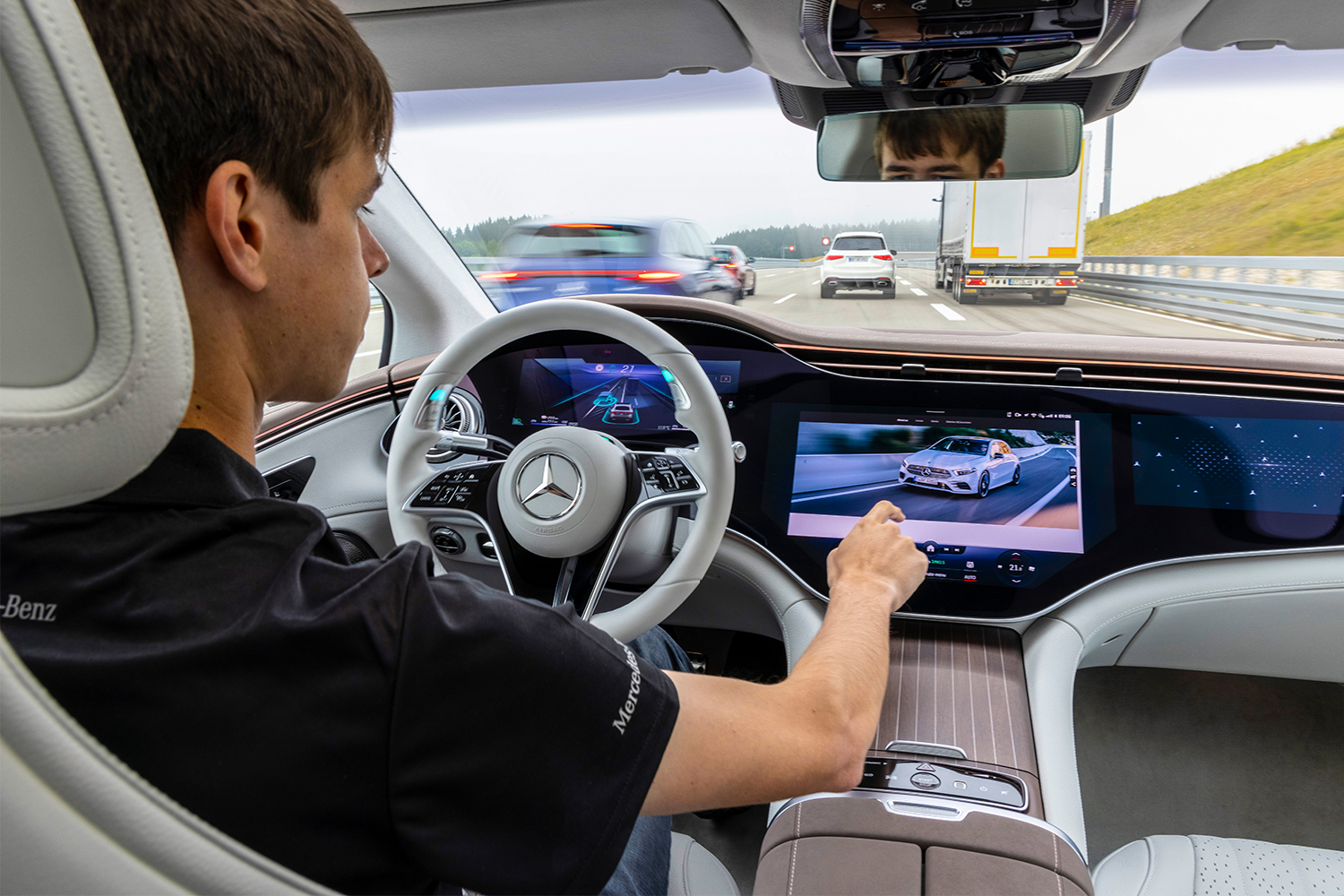 A man driving the Mercedes-Benz EQS luxury electric sedan and using the digital Hyperscreen
