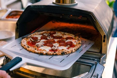 A pizza going into the Ooni Karu 16 Multi-Fuel Pizza Oven, now on sale for Black Friday