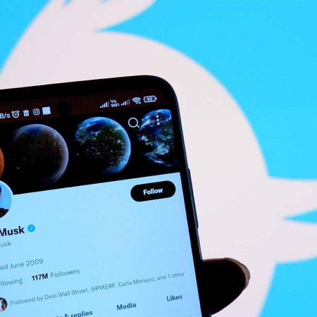 In this photo illustration, Twitter account of Elon Musk is displayed on a smartphone with a Twitter logo in the background. A former employee suggests Twitter may crash during the World Cup