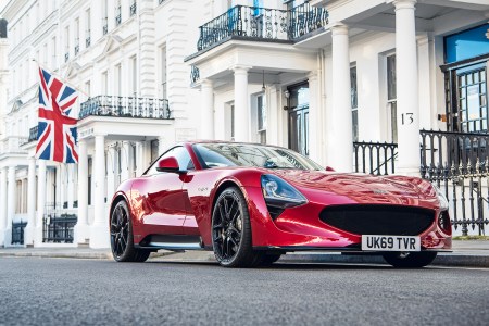 The TVR Griffith V8 sports car in red sitting in front of a British Union Jack flag hanging in the background