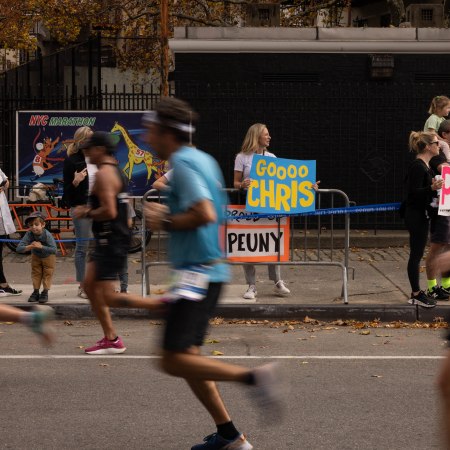 A woman holds a sign to cheer on runners at the New York City Marathon.