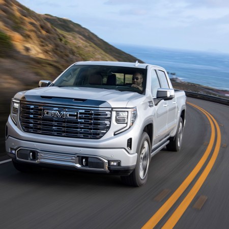 The 2022 GMC Sierra Denali Ultimate driving down a road next to the ocean. Here's our full review of the luxury pickup truck.