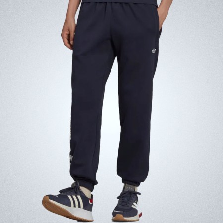a model in a pair of navy Adidas varsity sweatpants
