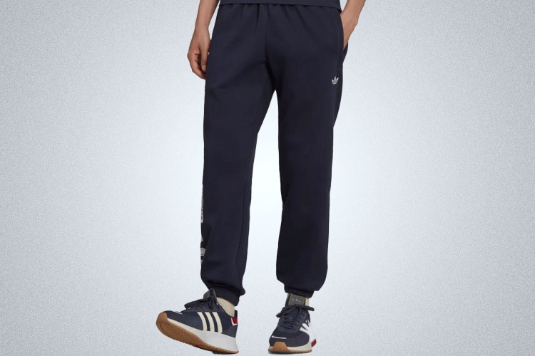 a model in a pair of navy Adidas varsity sweatpants
