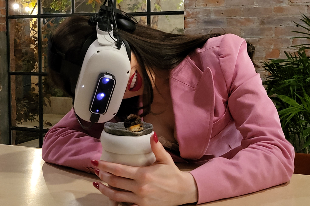 A woman eating a meal with a Meta Quest 2 VR headset at Aerobanquets in Brooklyn, New York in 2022
