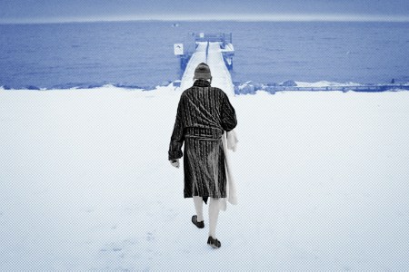 A robed man walking towards a dock in the snow.