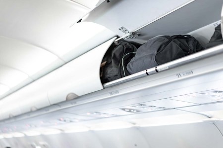 Luggage in the overhead storage bin above an airplane seat