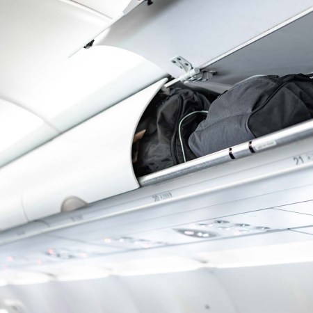 Luggage in the overhead storage bin above an airplane seat