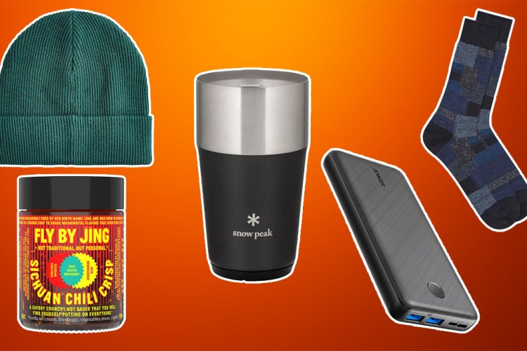 Stocking stuffer items like a snowpeak tumbler, J.Crew Beanie and Anker charger on a orange and rust colored background