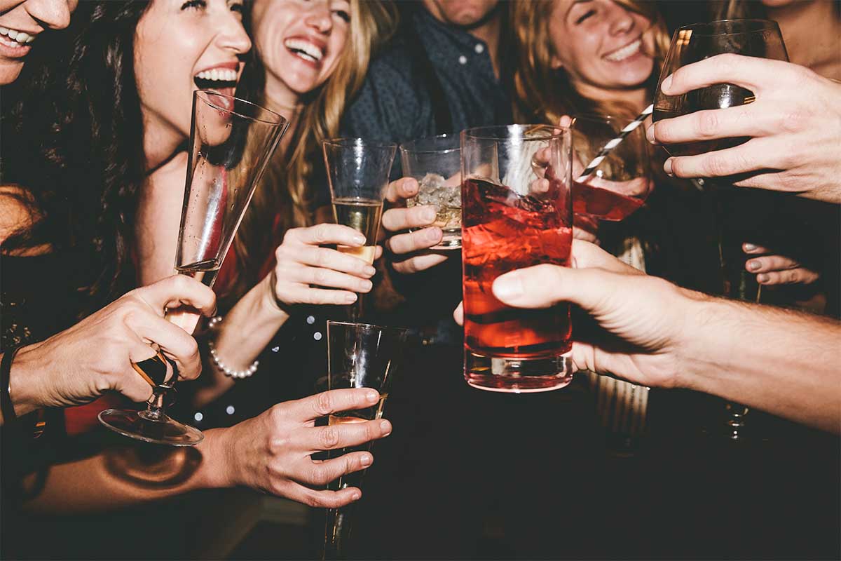 Cheerful male and female friends raising toast while partying together. A new Gallup report suggests young, male, white and rich people are more likely to drink than other demographic characteristics.
