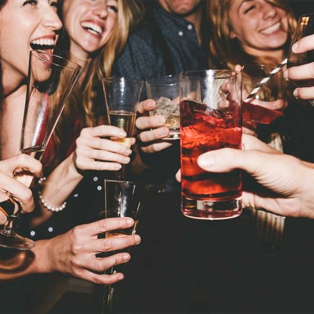 Cheerful male and female friends raising toast while partying together. A new Gallup report suggests young, male, white and rich people are more likely to drink than other demographic characteristics.