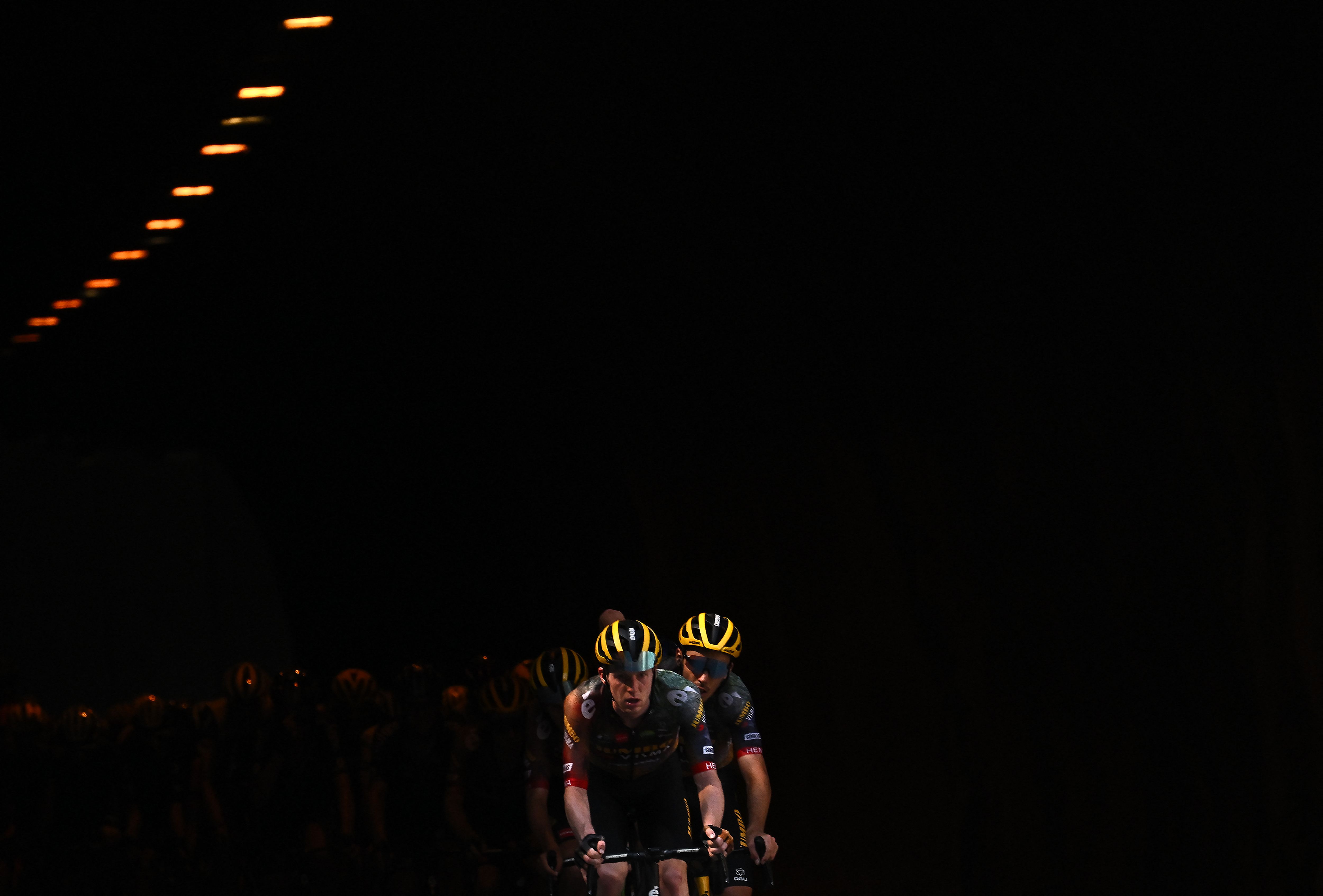 A Belgian cycling team emerges from a dark tunnel.