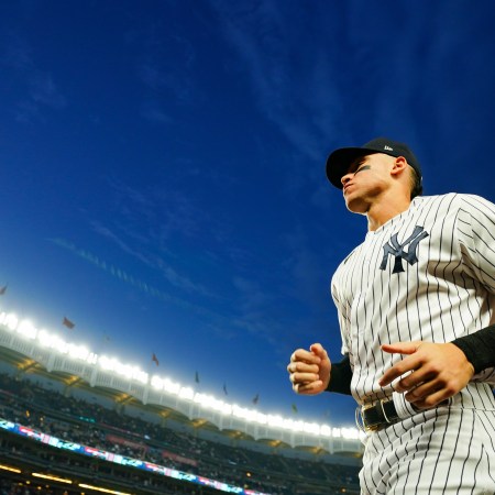 Aaron Judge running towards the dugout during a night game at Yankee Stadium.