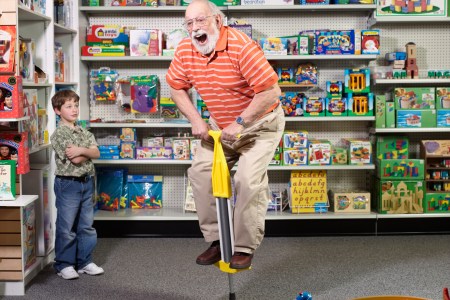 A grandfather using a pogo stick in a toy store.