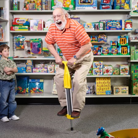 A grandfather using a pogo stick in a toy store.