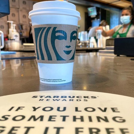 The Starbucks logo is displayed on a cup at a Starbucks store on October 29, 2021 in Marin City, California. Changes to Starbucks Rewards mean most customers will need to earn more stars to earn free coffee.