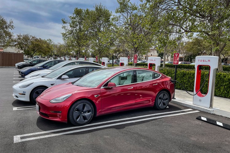 A row of Tesla electric vehicles filling their batteries at charging stations