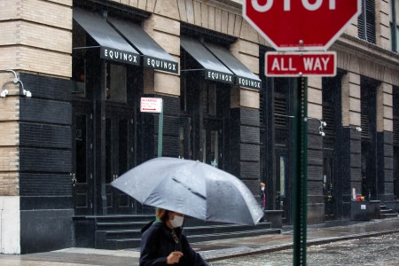 A woman walks past an Equinox in the rain.