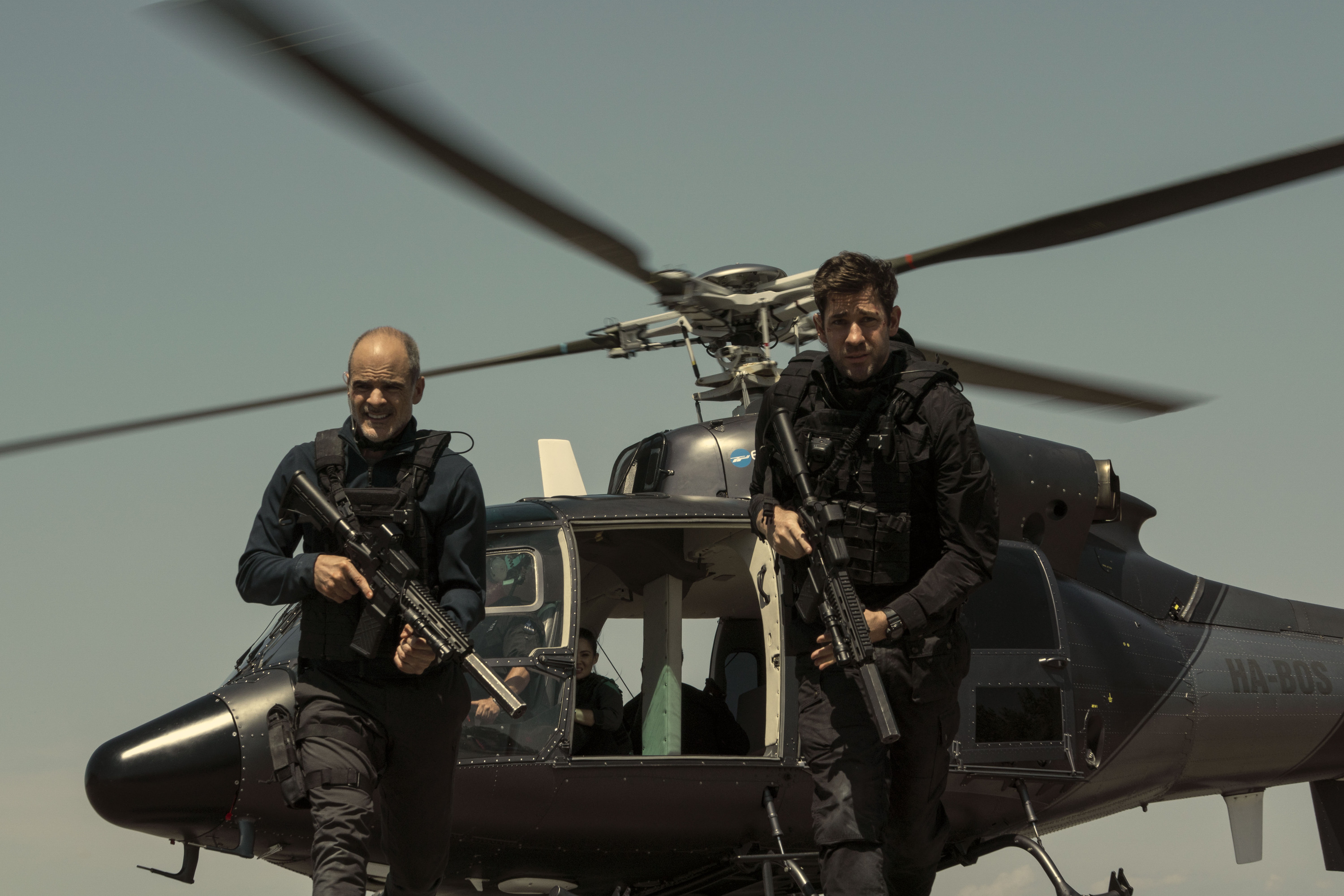 Jack Ryan walking from a helicopter with a gun.