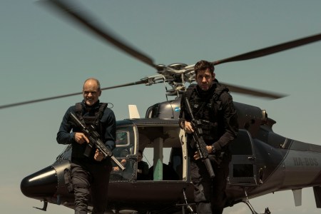 Jack Ryan walking from a helicopter with a gun.