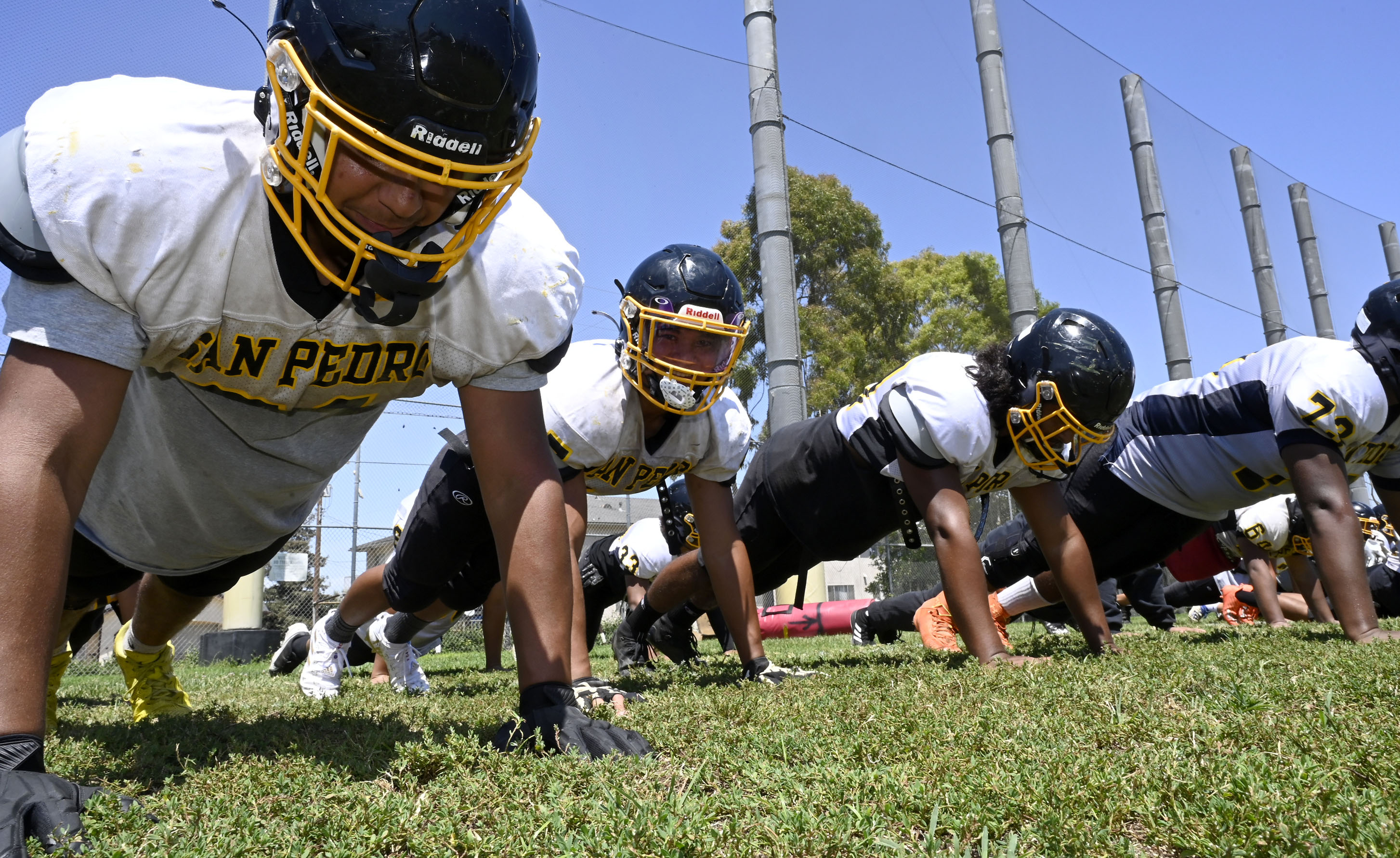 Members of a high school football team doing push-ups.