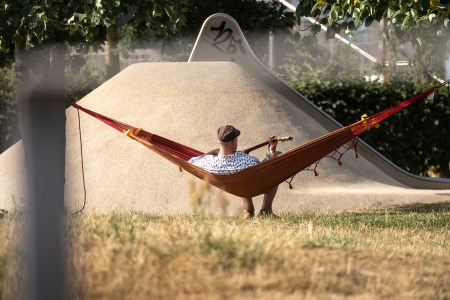 A man playing guitar on a hammock. People are suffering from "workplace burnout" and not taking advantage of weekends.