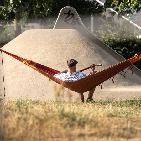A man playing guitar on a hammock. People are suffering from "workplace burnout" and not taking advantage of weekends.