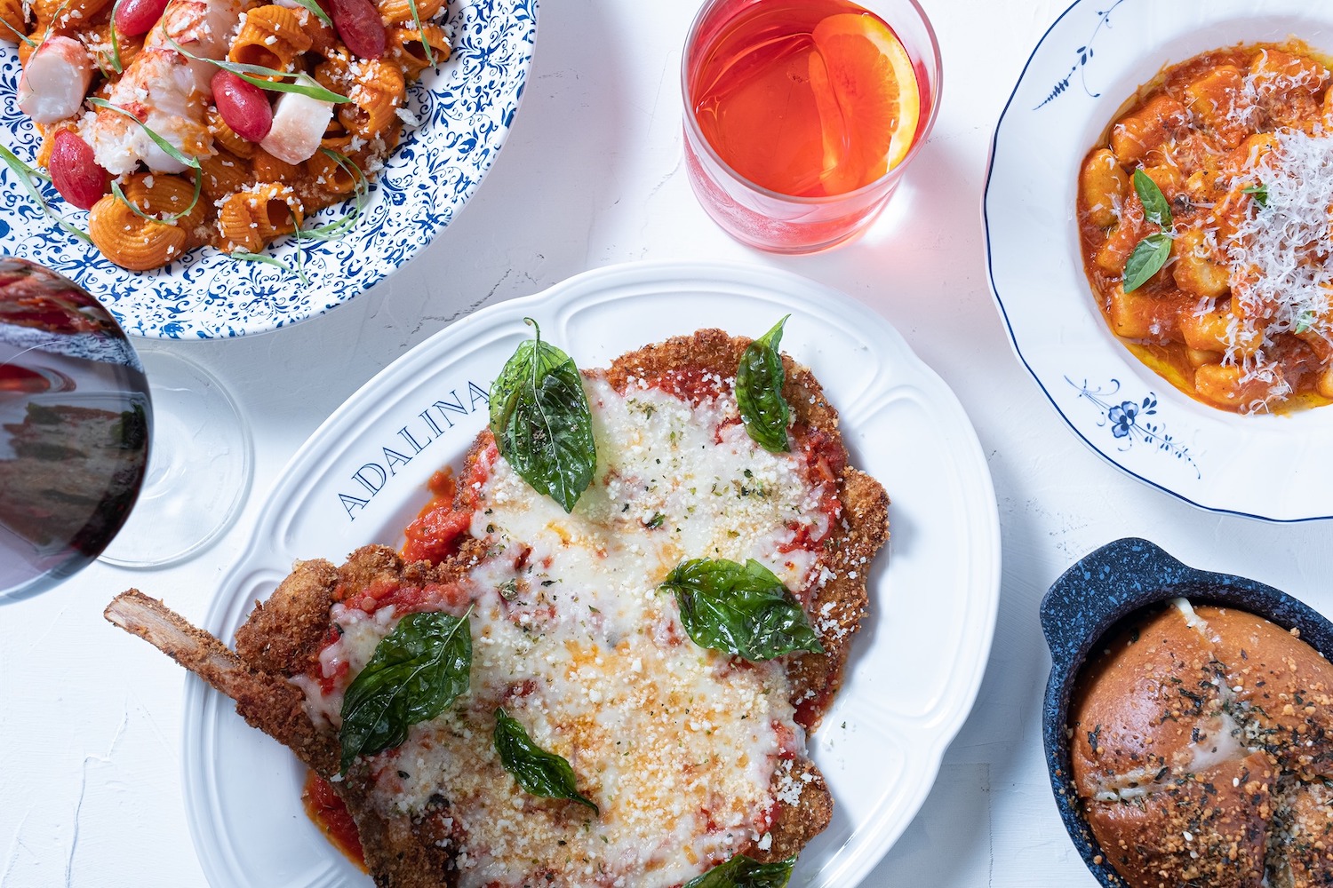 Spread of dishes and cocktails like pasta and chicken parm on a table