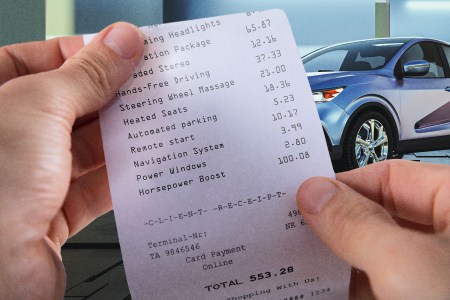 Hands holding a receipt for car feature subscriptions. Automakers are beginning to charge recurring subscription fees for certain features.
