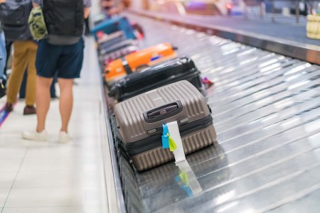 Luggage on a conveyor belt in an airport. If you're stuck waiting at a baggage carousel, you may be entitled to miles from your airline.